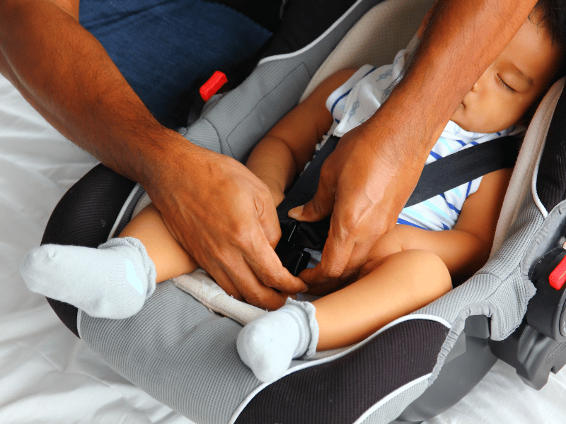 Child Being Strapped Into Car Safety Seat